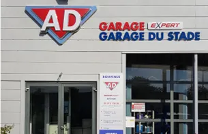 Enseigne AD Garage Expert rouge et bleue sur un bâtiment blanc avec une porte vitrée à Auneau en Eure-et-Loir 28